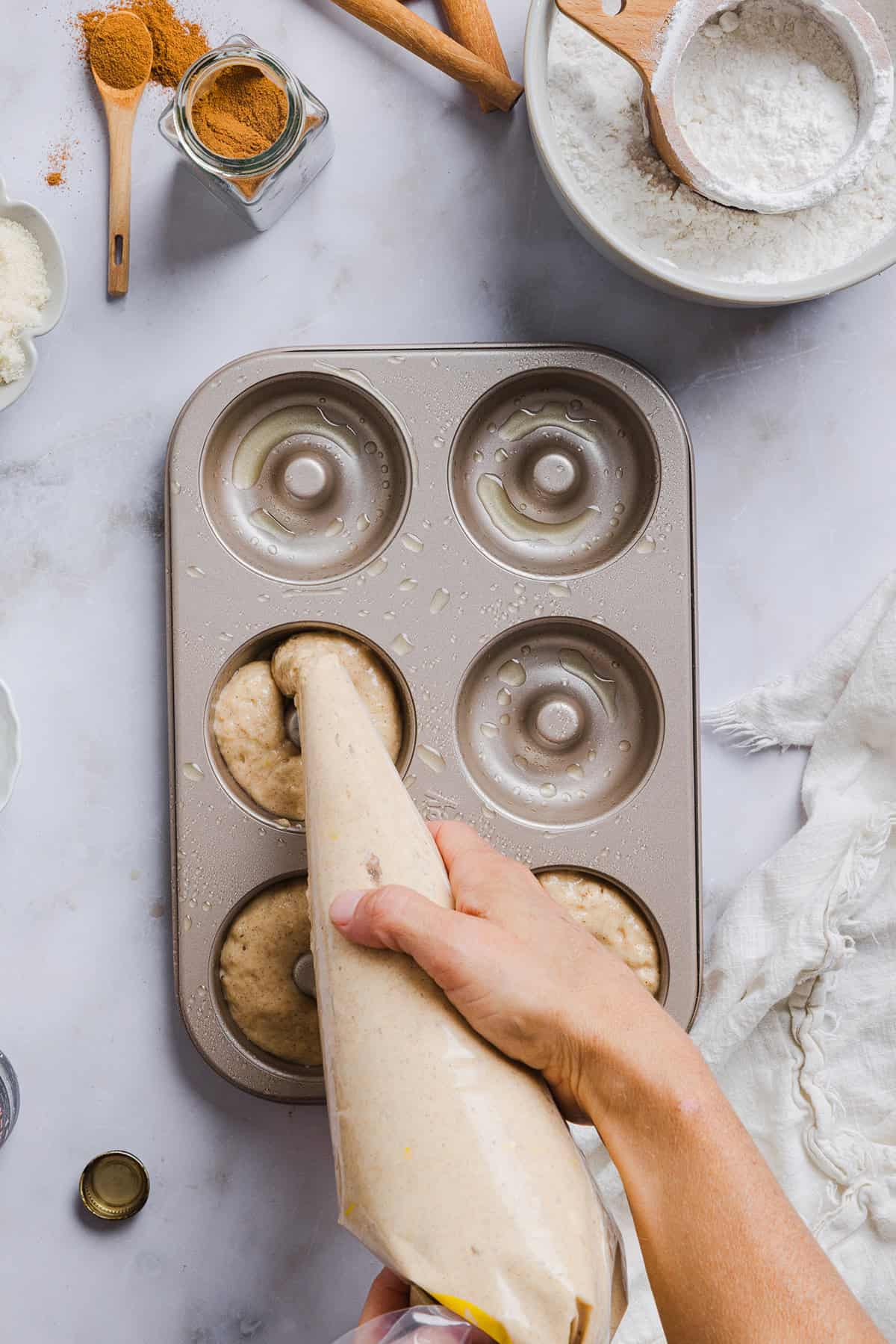 Soft Baked Apple Cider Donuts made healthier with whole wheat flour, applesauce and Greek yogurt for the perfect fall treat that comes together in just 20 minutes! Loaded with warm spices and coated with cinnamon and sugar!