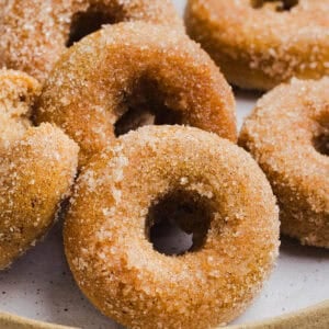 Soft Baked Apple Cider Donuts made healthier with whole wheat flour, applesauce and Greek yogurt for the perfect fall treat that comes together in just 20 minutes! Loaded with warm spices and coated with cinnamon and sugar!